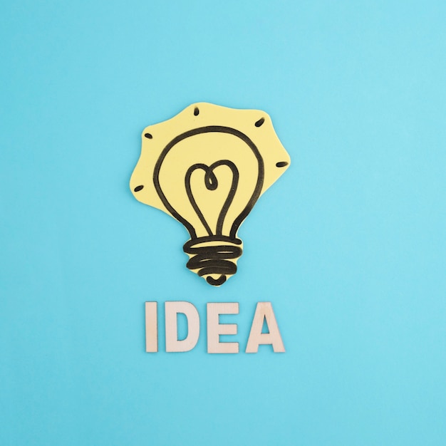 Free Photo idea word with drawn yellow light bulb on blue backdrop