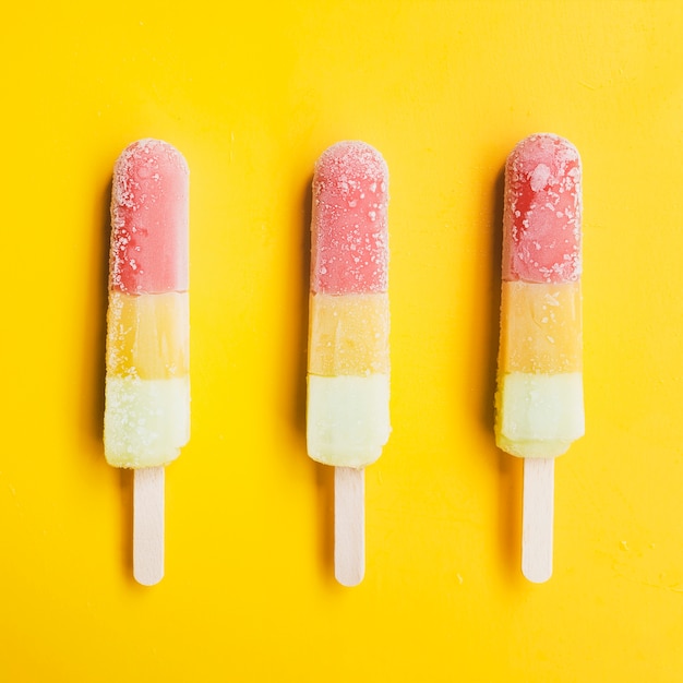 Free photo identical ice lollies on yellow background