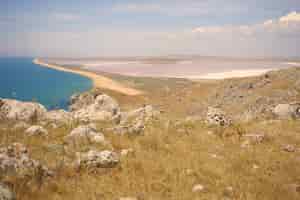 Free photo idyllic beautiful summer landscape of valley, calm turquoise sea and rocky surface on top of hill. enjoying sunny day in wild nature. seascape, mountains, tourist attraction and adventure concept