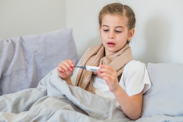 Ill girl using thermometer