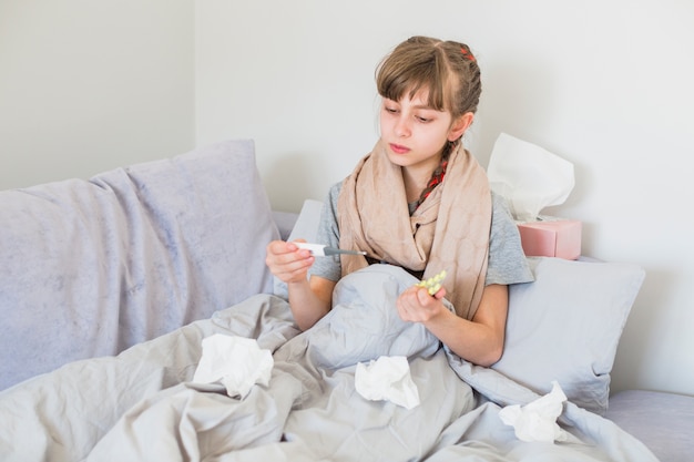 Ill girl using thermometer