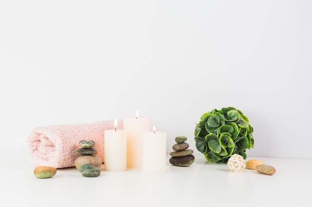 Free Photo illuminated candles; towel; spa stones on white tabletop