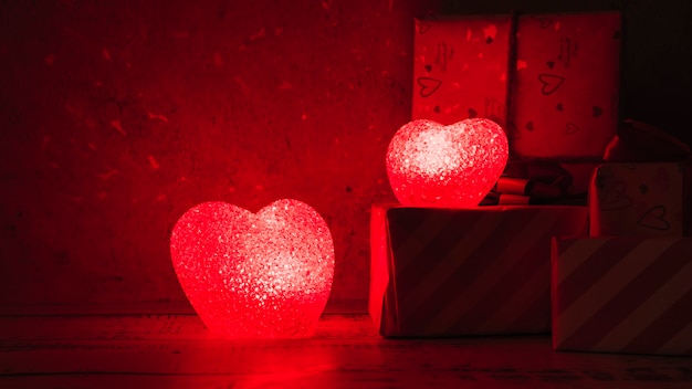 Free Photo illuminated lamps in form of hearts near gift boxes