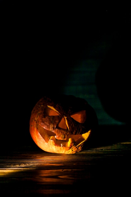 Free photo illuminated pumpkin on wooden desk