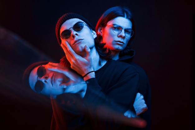 Illusion of three faces. Portrait of twin brothers. Studio shot in dark studio with neon light