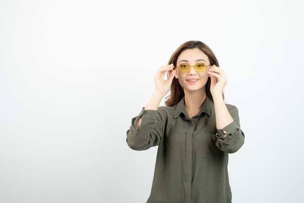 Image of adorable girl in glasses standing over white wall. High quality photo