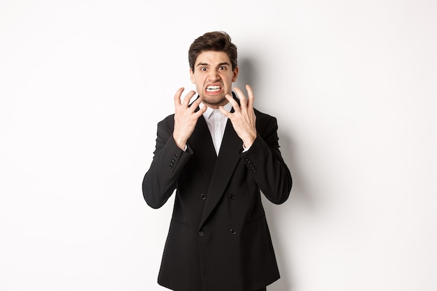 Free Photo image of angry businessman in suit, looking with furious expression and clenching fists, express hatred, standing mad over white background