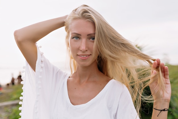 Image of a carefree smiling woman in a white blouse spending leisure time on the beach. Summer mood. Sunny day