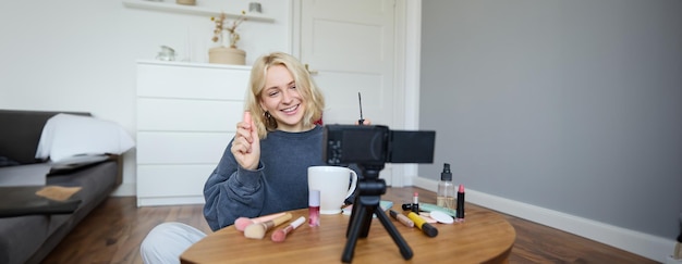 Free photo image of cheerful beautiful young lifestyle blogger woman sitting on floor and recording video about