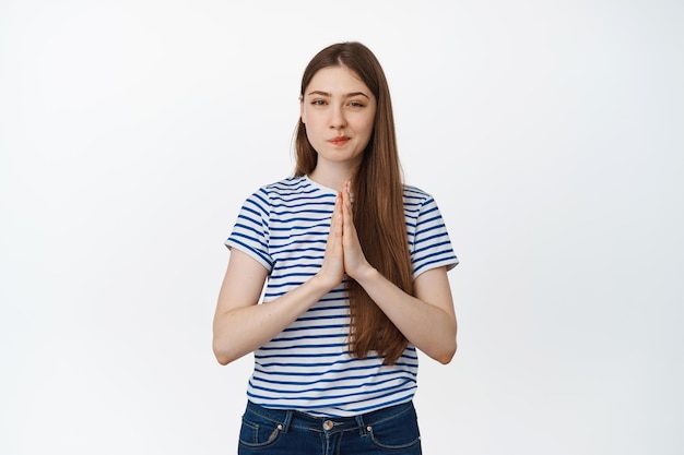 Free photo image of coy, thoughtful woman rub hands and look with smug face at camera, scheming, has an evil plan, stands against white background.