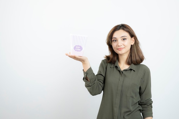 Image of cute girl with popcorn box posing to camera. High quality photo