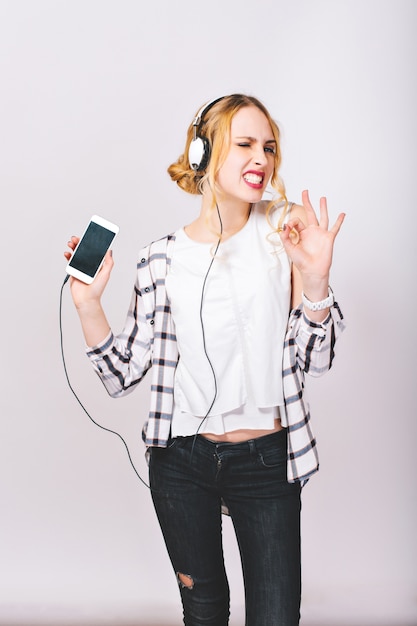 Image of delighted cute cheerful girl listening to music and enjoying her exciting life so much.  Happy and positive mood. Slim body. Satisfied face. Bright emotions.