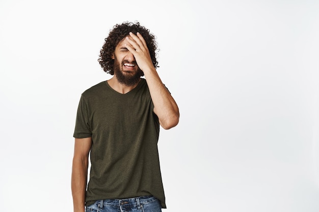 Free photo image of frustrated young man failing feeling upset making facepalm from regret standing disappointed against white background