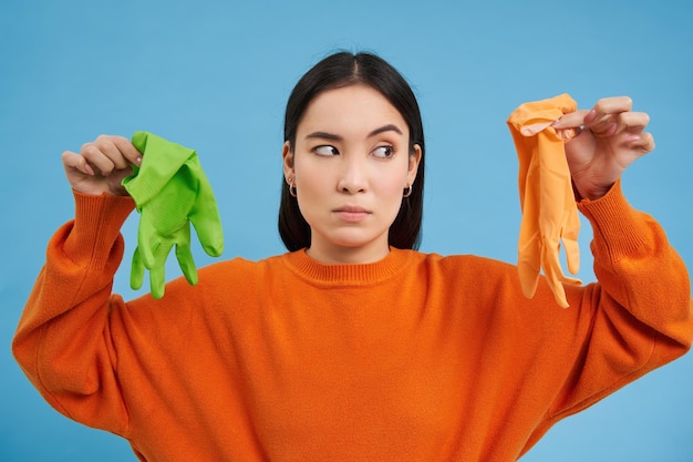 Free Photo image of girl with bothered face showing two dirty cleaning gloves found garbage looking disappointe