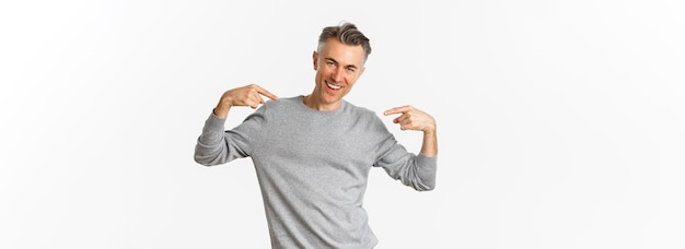 Free photo image of handsome and confident middleaged man with short grey hairstyle pointing at himself and smi