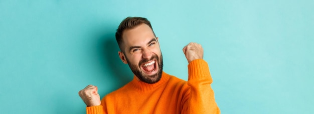 Free photo image of handsome relieved man feeling satisfaction rejoicing of winning or achievement making fist