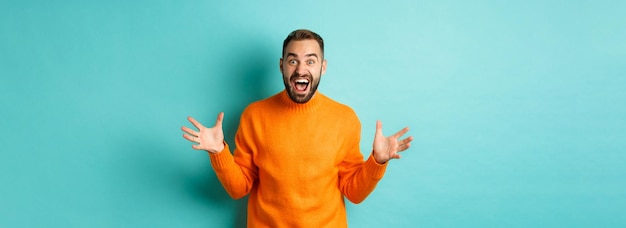 Free photo image of happy and excited man announce big news spread hands and shouting of joy rejoicing standing