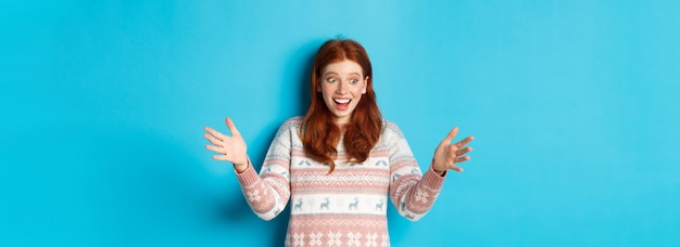 Free photo image of happy redhead girl holding big size object looking amazed and smiling receiving christmas g