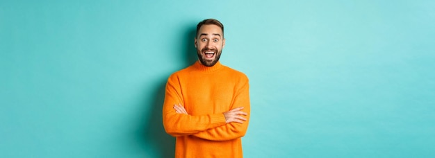 Free photo image of happy and surprised man reacting to news looking amazed standing in orange sweater against