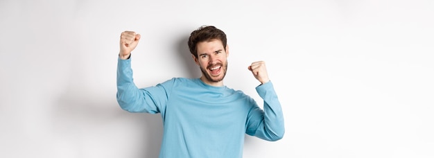 Free photo image of happy young man triumphing feeling like champion winning and screaming in cheer standing ov