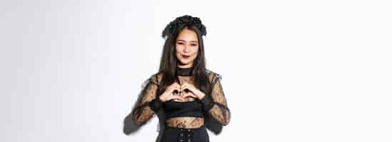 Free photo image of lovely smiling asian woman love celebrating halloween showing heart gesture and looking at