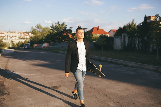 Image of a man with longboard going on road