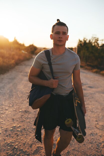 Image of a man with longboard going on road