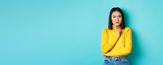 Free photo image of pensive asian woman touching lip and frowning thinking about something trying to understand