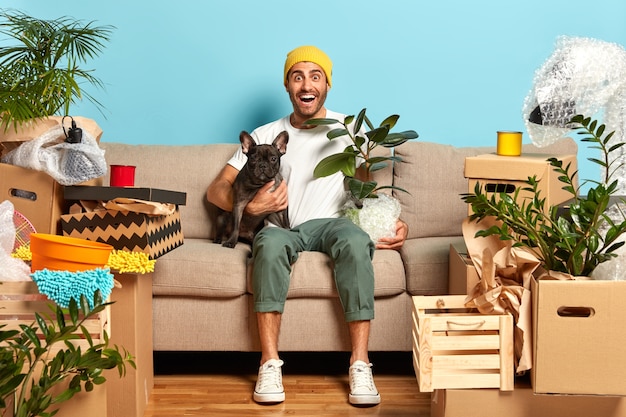 Image of positive fashionable guy rents new flat, lives together with favourite dog