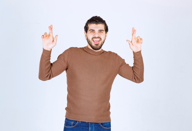 Free Photo image of positive young man isolated over white background showing hopeful please fingers crossed gesture. high quality photo