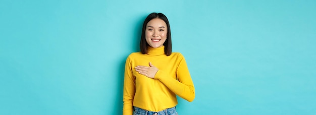 Free Photo image of proud smiling asian woman holding hand on heart showing respect to national anthem standing