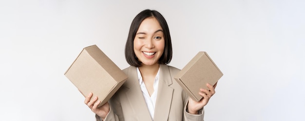 Image of saleswoman asian businesswoman holding boxes with company brand product smiling at camera s