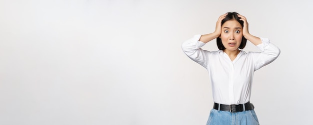 Free Photo image of shocked anxious asian woman in panic holding hands on head and worrying standing frustrated