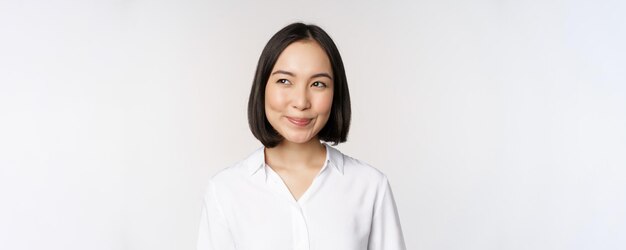 Image of smiling asian woman planning thinking of smth daydreaming standing over white background wi