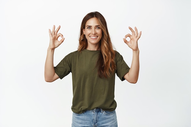 Image of smiling middle-aged woman with perfect skin, white smile, showing okay sign OK, approve and praise awesome store, recommending company service, white background