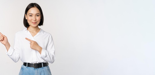 Image of smiling young office lady asian business entrepreneur pointing fingers left showing client