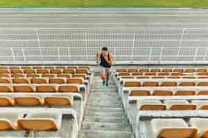 Free photo image of young athletic man running by ladder at the stadium out