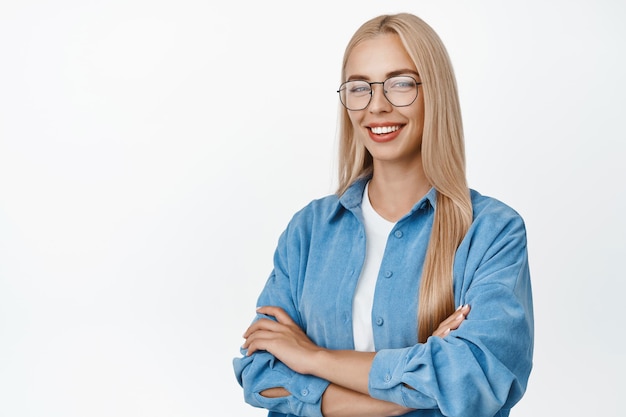 Image of young blond woman in glasses standing like professional smiling and looking confident cross arms on chest standing over white background