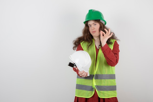 Image of a young cute girl with down syndrome standing in vest showing ok gesture .