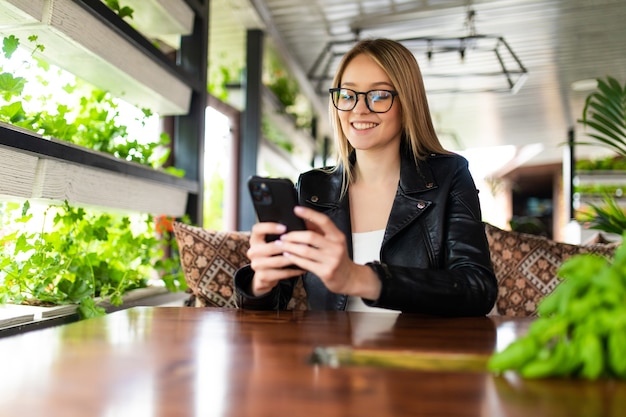 Image of young female reading sms on the phone in cafe