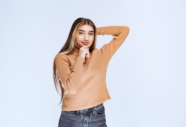 Image of a young woman model in brown sweater standing and posing.