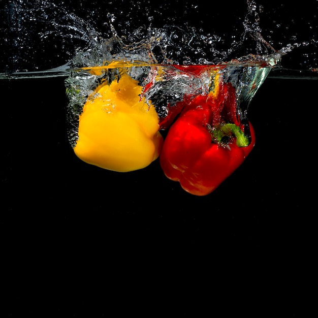 Free Photo impact of bell pepper falling into water on black background