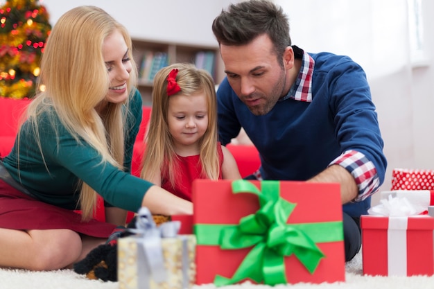 Free Photo impatient little girl opening christmas presents with parents