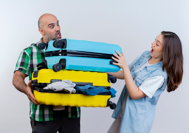 Impressed adult traveler couple man holding suitcases woman putting hand on one of them both looking at suitcases 