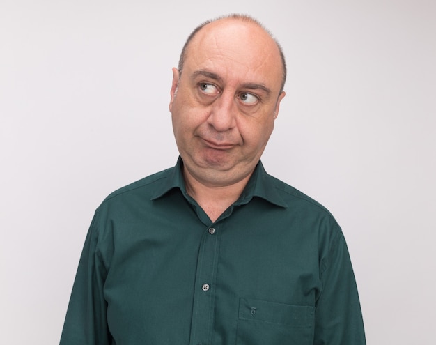 Impressed looking at side middle-aged man wearing green t-shirt isolated on white wall