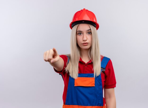 Impressed young blonde engineer builder girl in uniform pointing  on isolated white space with copy space