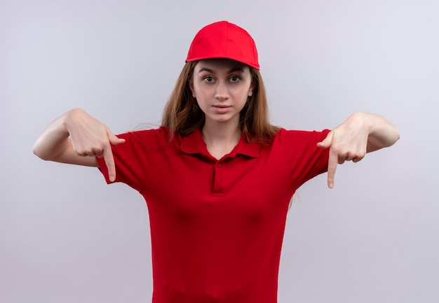 Free photo impressed young delivery girl in red uniform pointing with fingers down on isolated white space