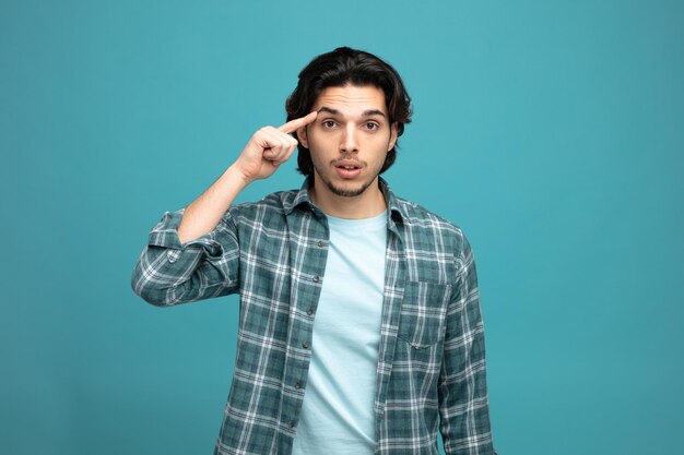 impressed young handsome man looking at camera showing think gesture isolated on blue background