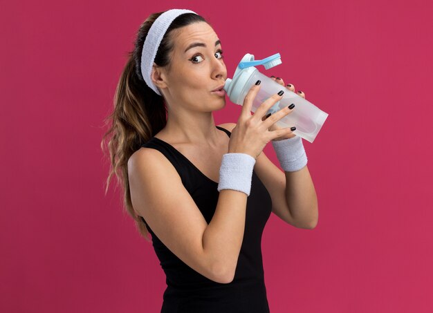 Impressed young pretty sporty girl wearing headband and wristbands 