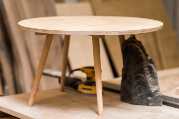 Free photo incomplete small round wooden table on workbench